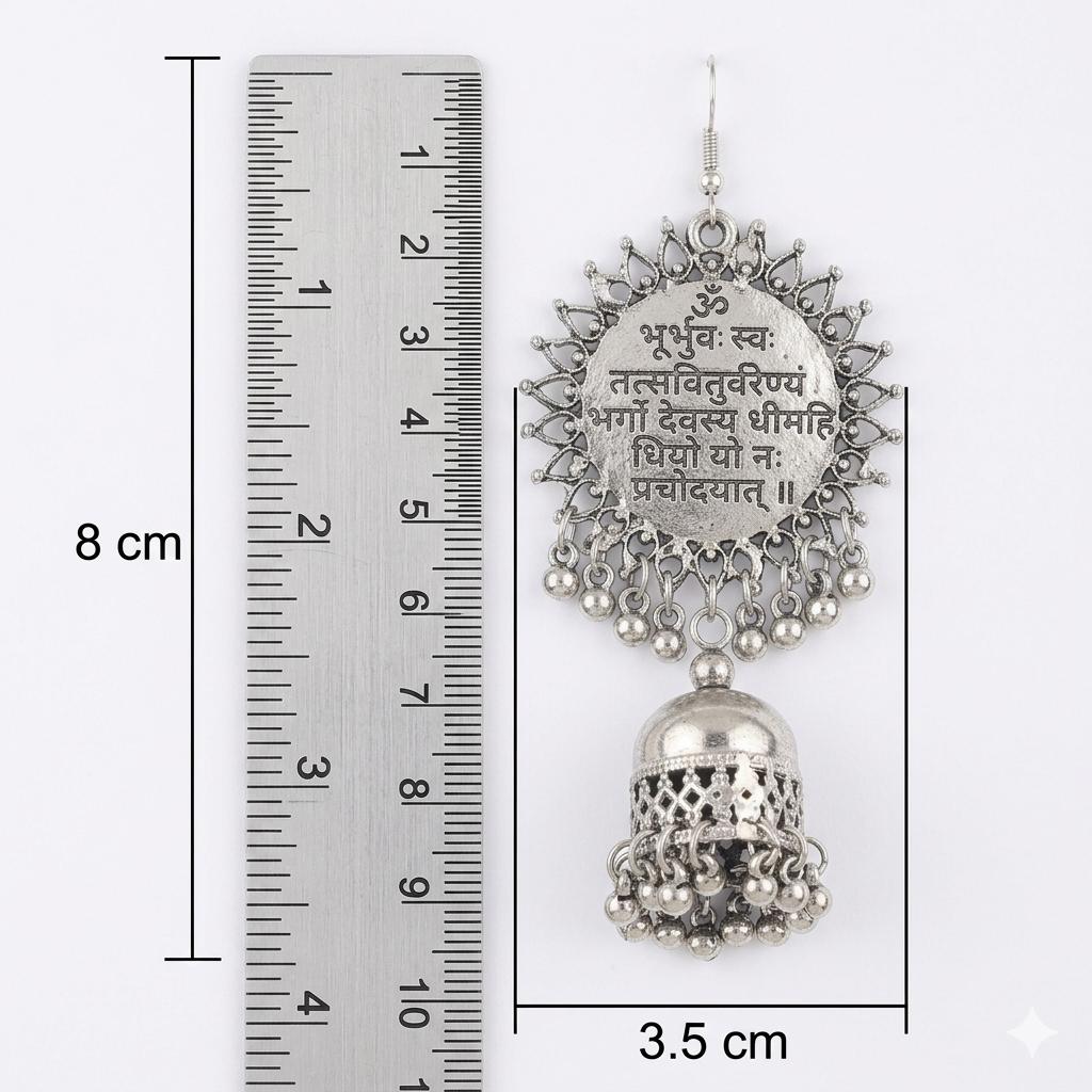 Silver earrings with intricate designs and text, shown with a ruler for scale on a white background.