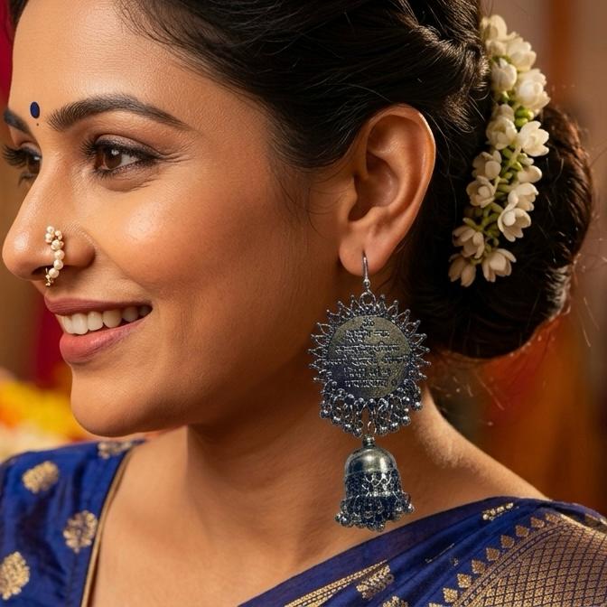 Woman wearing a blue saree with silver jewelry, including earrings and a nose ring.